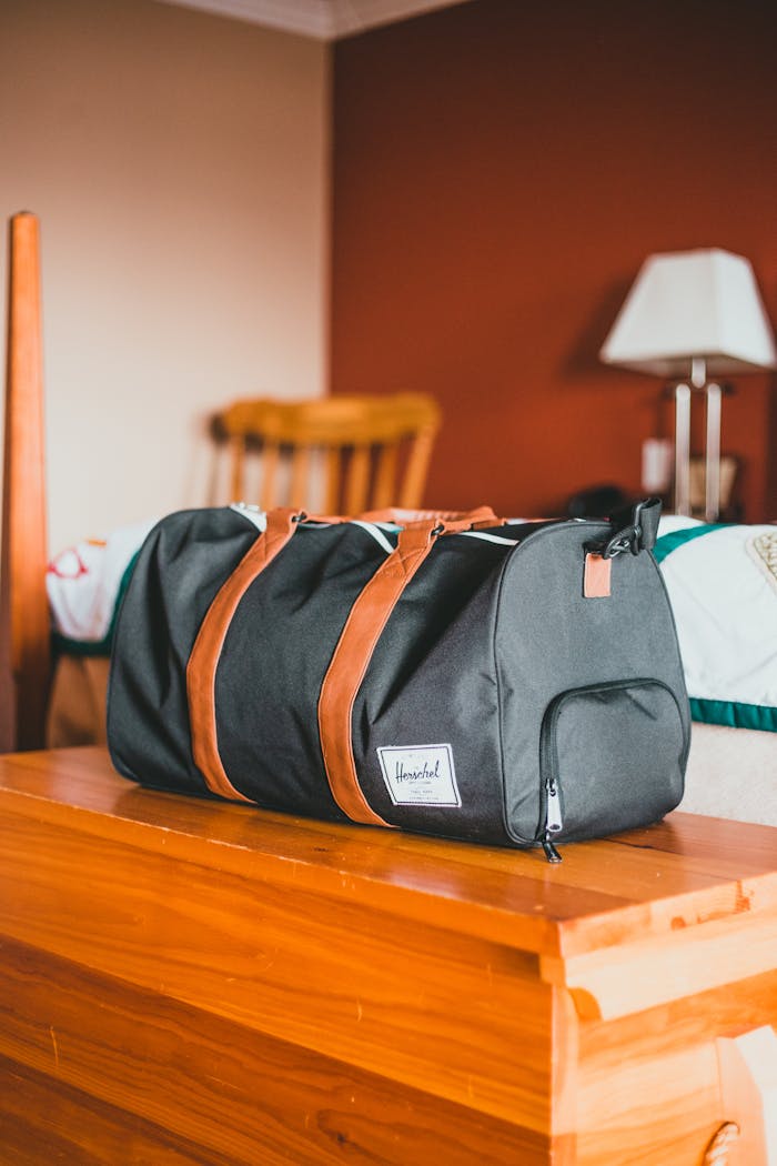 Elegant black gym bag with brown straps on a wooden table in a warm home setting.